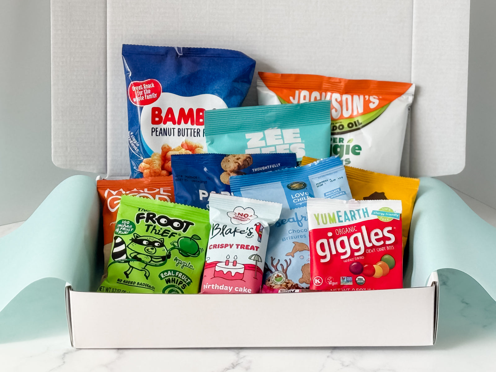 Assorted snack packs in a box on a light gray surface