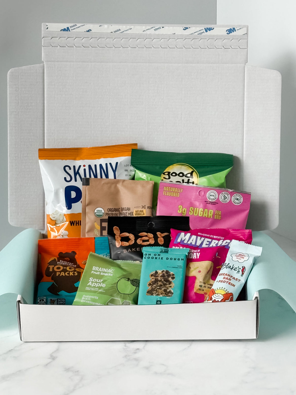 Assorted snack packets in a box on a marble surface
